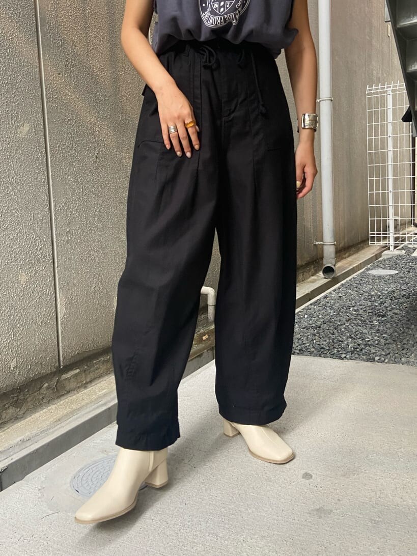 ベージュ系のトレンチコート、ブラック系のその他パンツ、ホワイト系のブーツを着用したレディースの夏コーディネートの3枚目の写真
