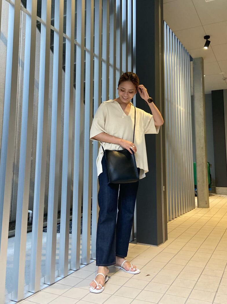 ホワイト系のサンダル、ホワイト系のニット/セーター、ブルー系のデニムパンツを着用したレディースの夏コーディネートの2枚目の写真