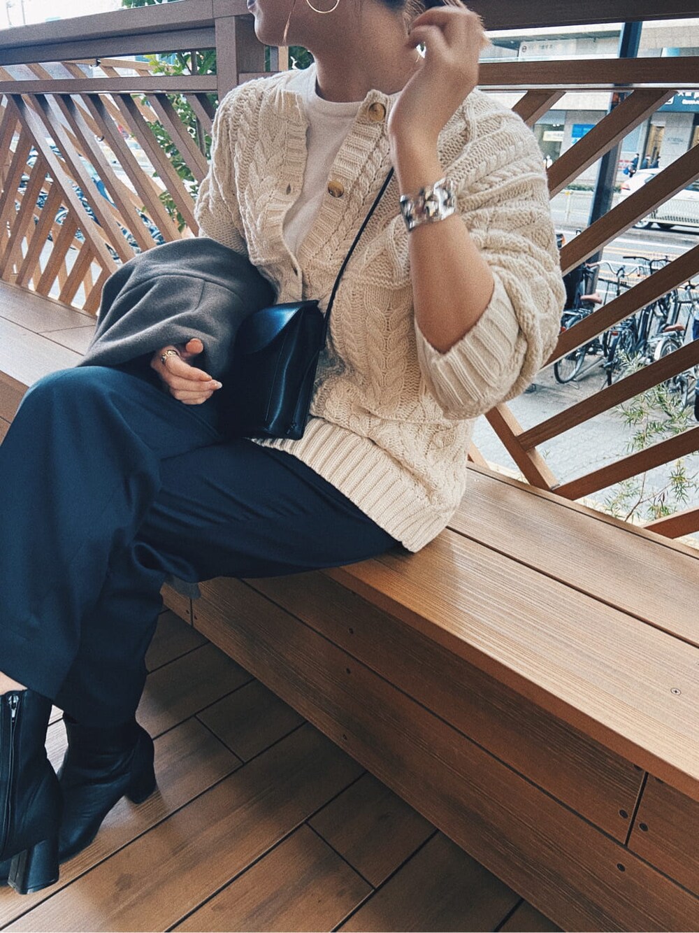 ブラック系のショルダーバッグ、ホワイト系のカーディガン/ボレロ、グレー系のその他パンツを着用したレディースの冬コーディネートの2枚目の写真