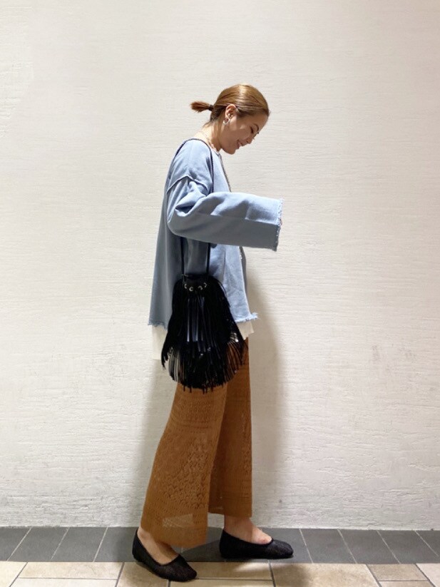 ブラック系のハンドバッグ、ブラウン系のスカート、ブラック系のTシャツ/カットソーを着用したレディースの春コーディネートの2枚目の写真