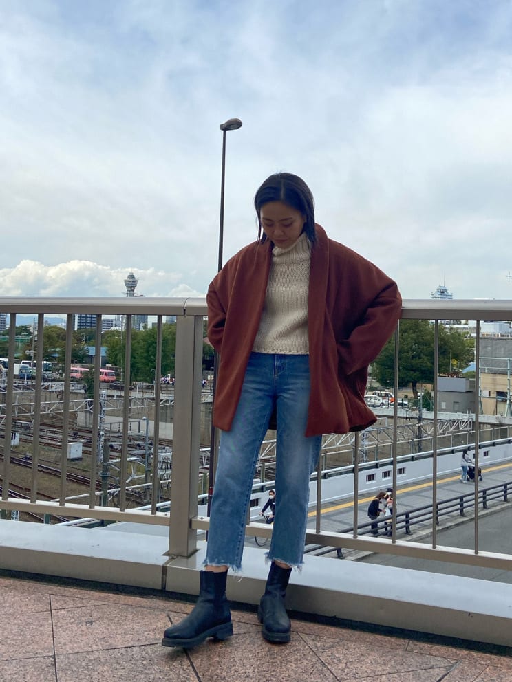 オレンジ系のその他アウター、ブルー系のデニムパンツ、ホワイト系のニット/セーターを着用したレディースの秋コーディネートの2枚目の写真