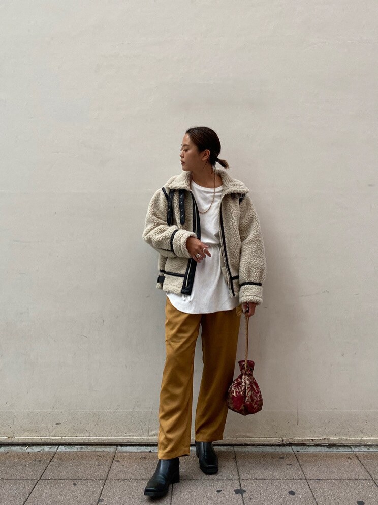 レッド系のハンドバッグ、ホワイト系のTシャツ/カットソー、ブラック系のブーツを着用したレディースの秋コーディネートの2枚目の写真