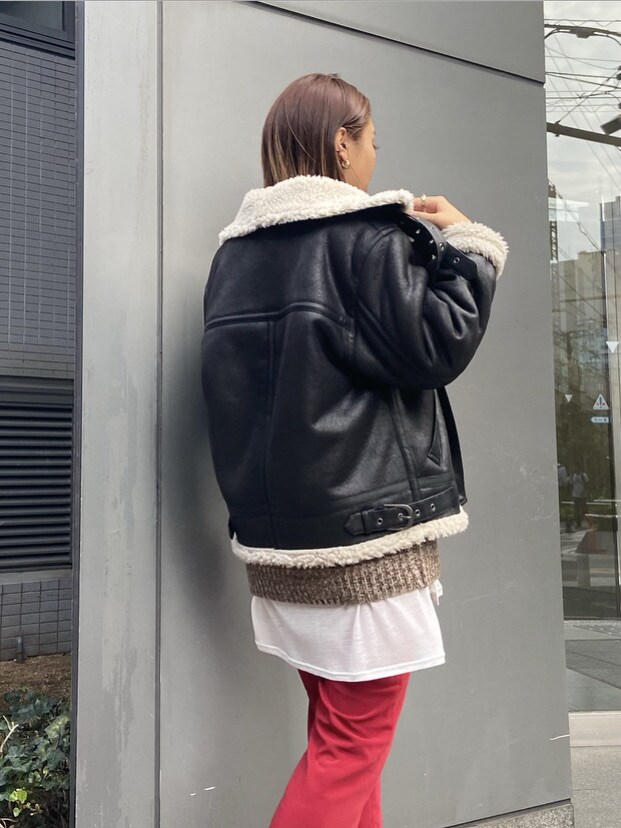 ホワイト系のTシャツ/カットソー、ブラック系のムートンコート、レッド系のその他パンツを着用したレディースの秋コーディネートの2枚目の写真