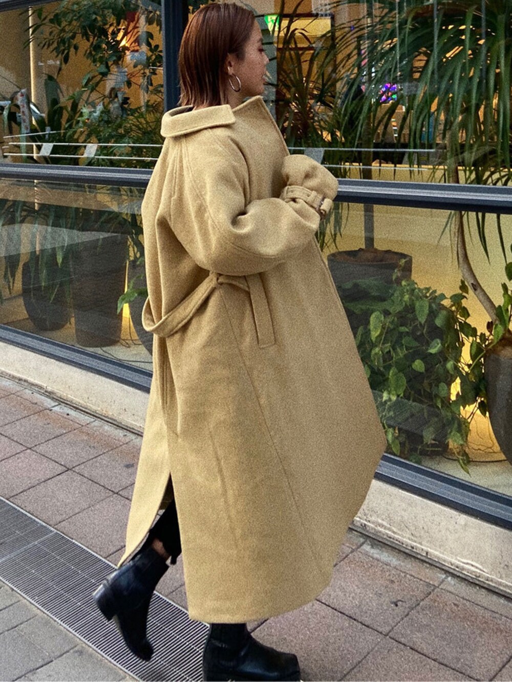 ブラック系のデニムパンツ、ブラック系のニット/セーター、イエロー系のステンカラーコートを着用したレディースの冬コーディネートの3枚目の写真