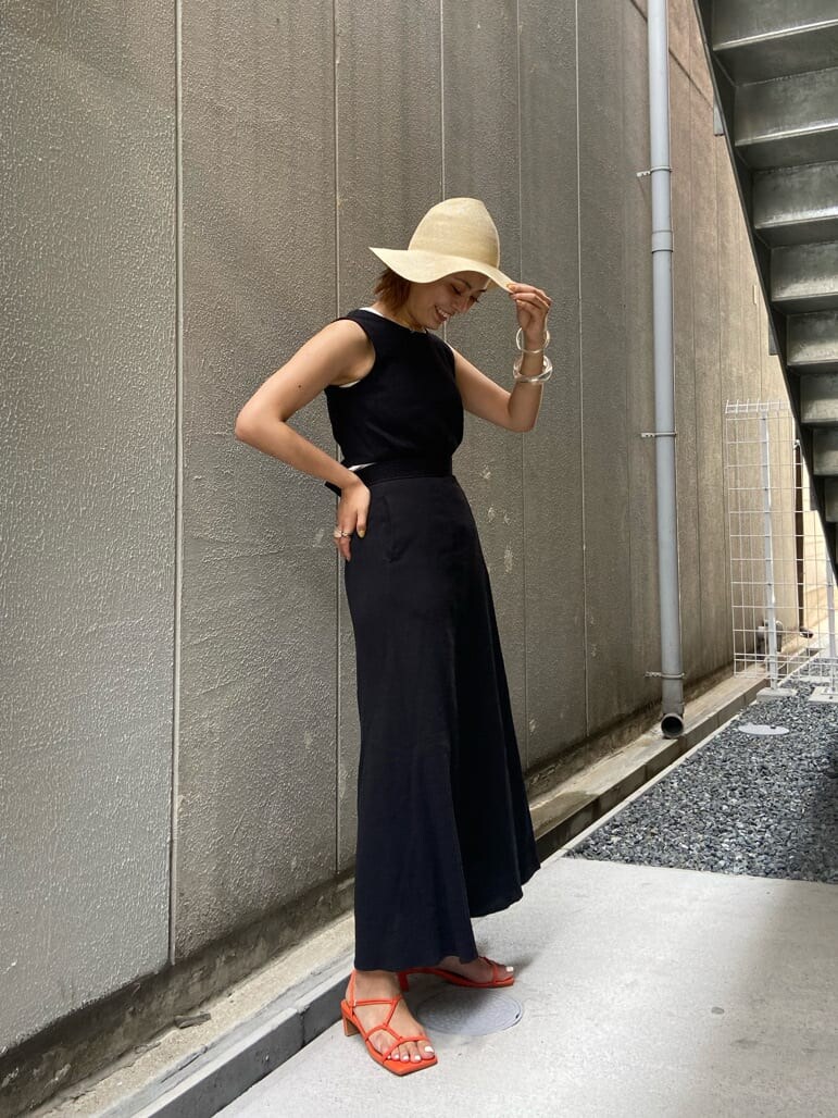 オレンジ系のサンダル、ブラック系のワンピースを着用したレディースの夏コーディネートの2枚目の写真