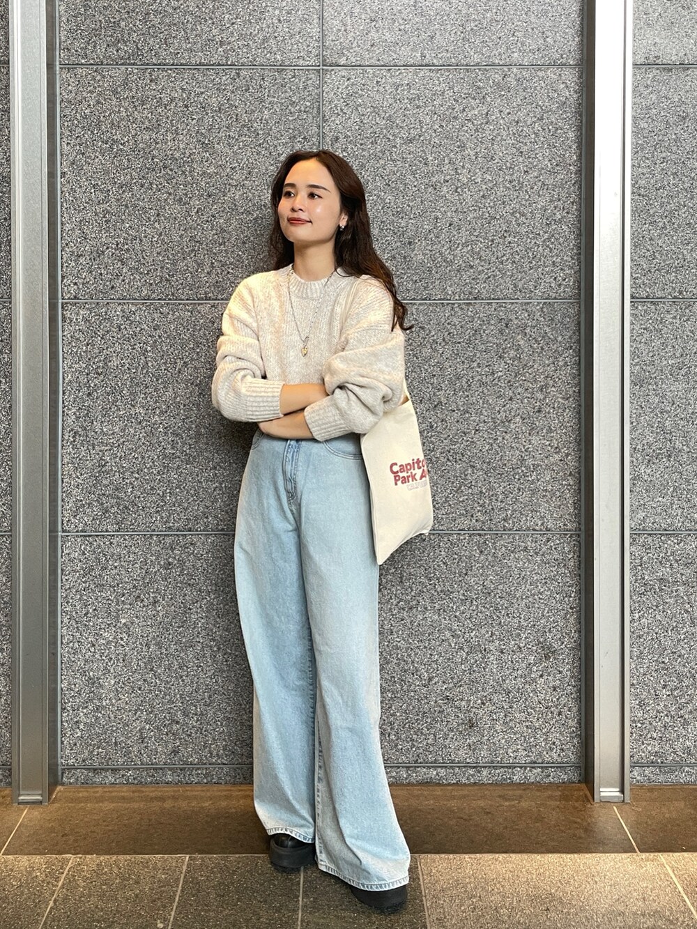 ブルー系のデニムパンツ、ホワイト系のニット/セーター、レッド系のトートバッグを着用したレディースの秋コーディネートの7枚目の写真