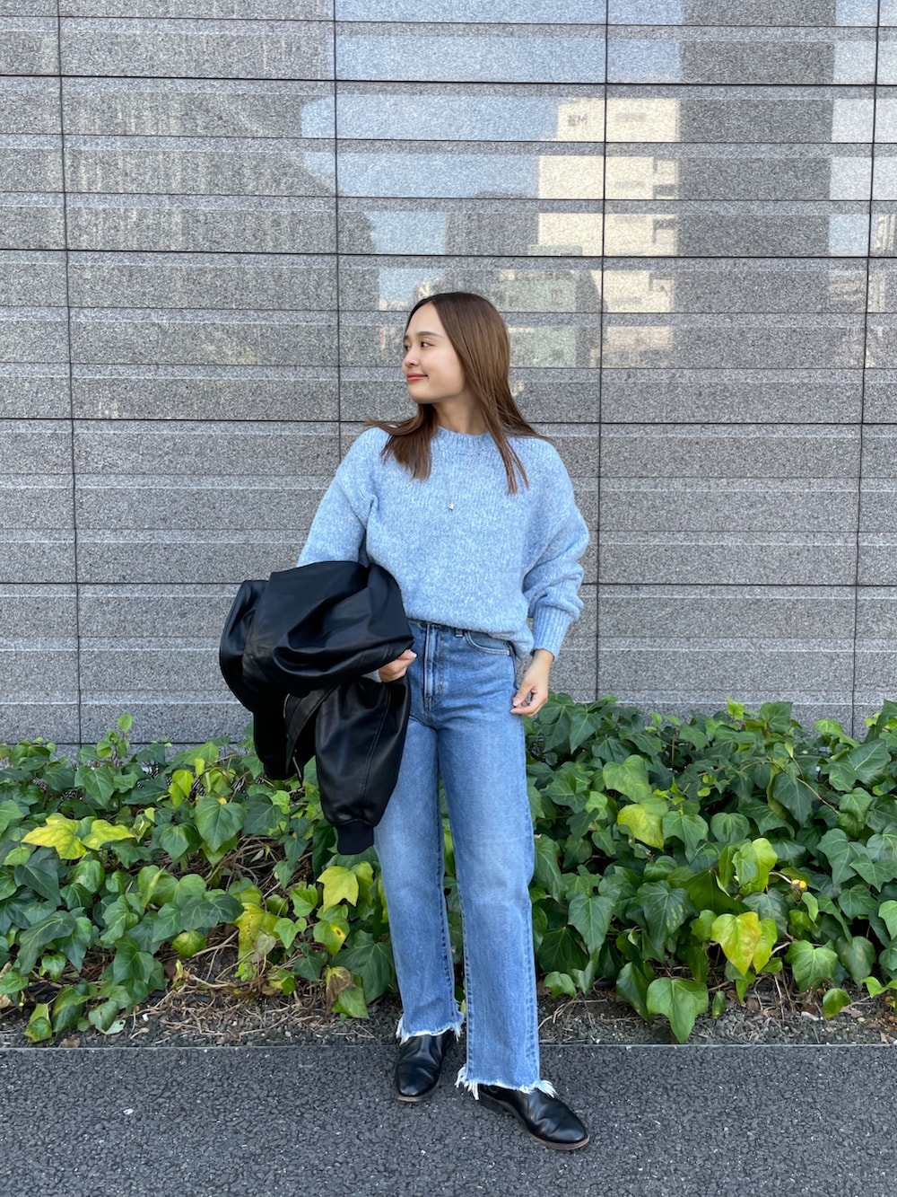 ブラック系のブルゾン、ブルー系のニット/セーター、ブルー系のデニムパンツを着用したレディースの秋コーディネートの8枚目の写真