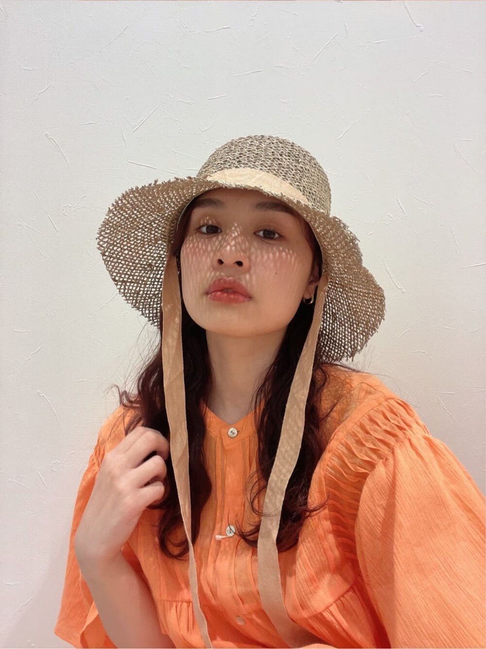 オレンジ系のワンピース、ベージュ系のハットを着用したレディースの春コーディネートの4枚目の写真