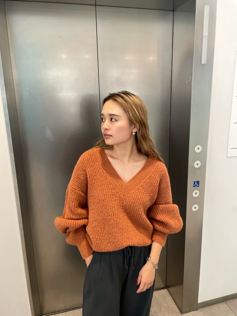 オレンジ系のニット/セーター、グレー系のスウェットパンツを着用したレディースの秋コーディネートの5枚目の写真