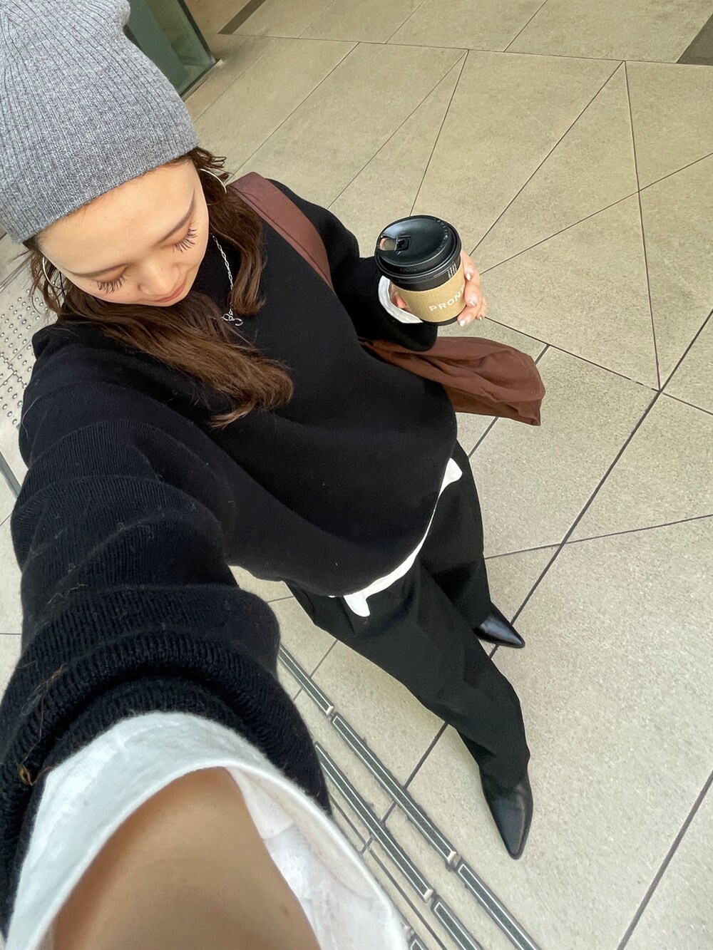 ブラック系のニット/セーター、ホワイト系のTシャツ/カットソー、ブラウン系のトートバッグを着用したレディースの冬コーディネートの3枚目の写真