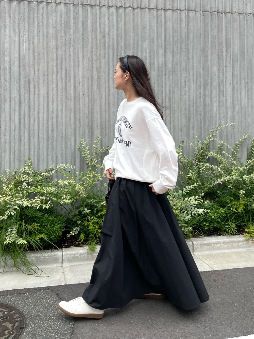 ホワイト系のスウェット、ブラック系のスカート、ブラック系のショルダーバッグを着用したレディースの夏コーディネートの5枚目の写真