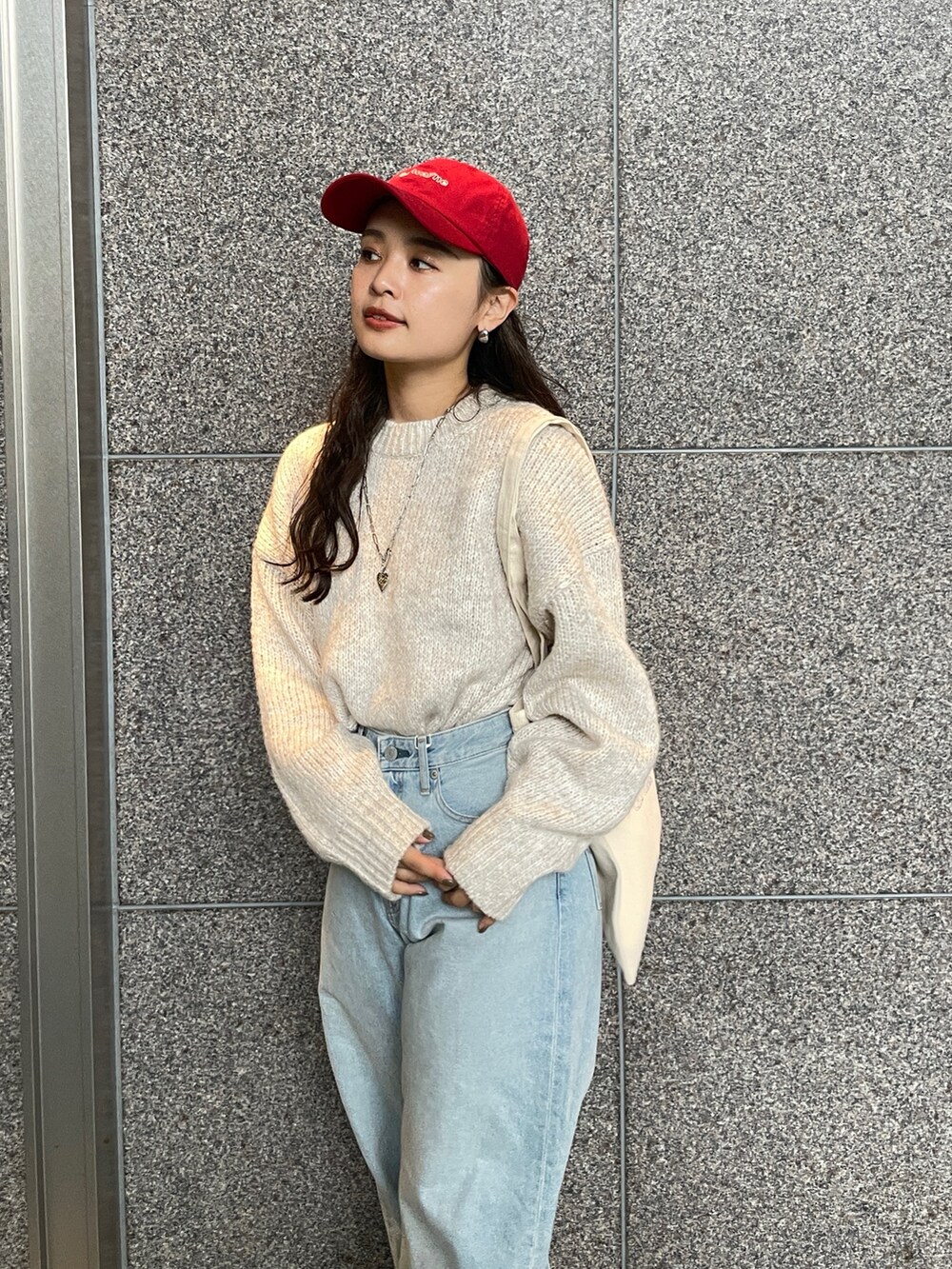 ブルー系のデニムパンツ、ホワイト系のニット/セーター、レッド系のトートバッグを着用したレディースの秋コーディネートの6枚目の写真