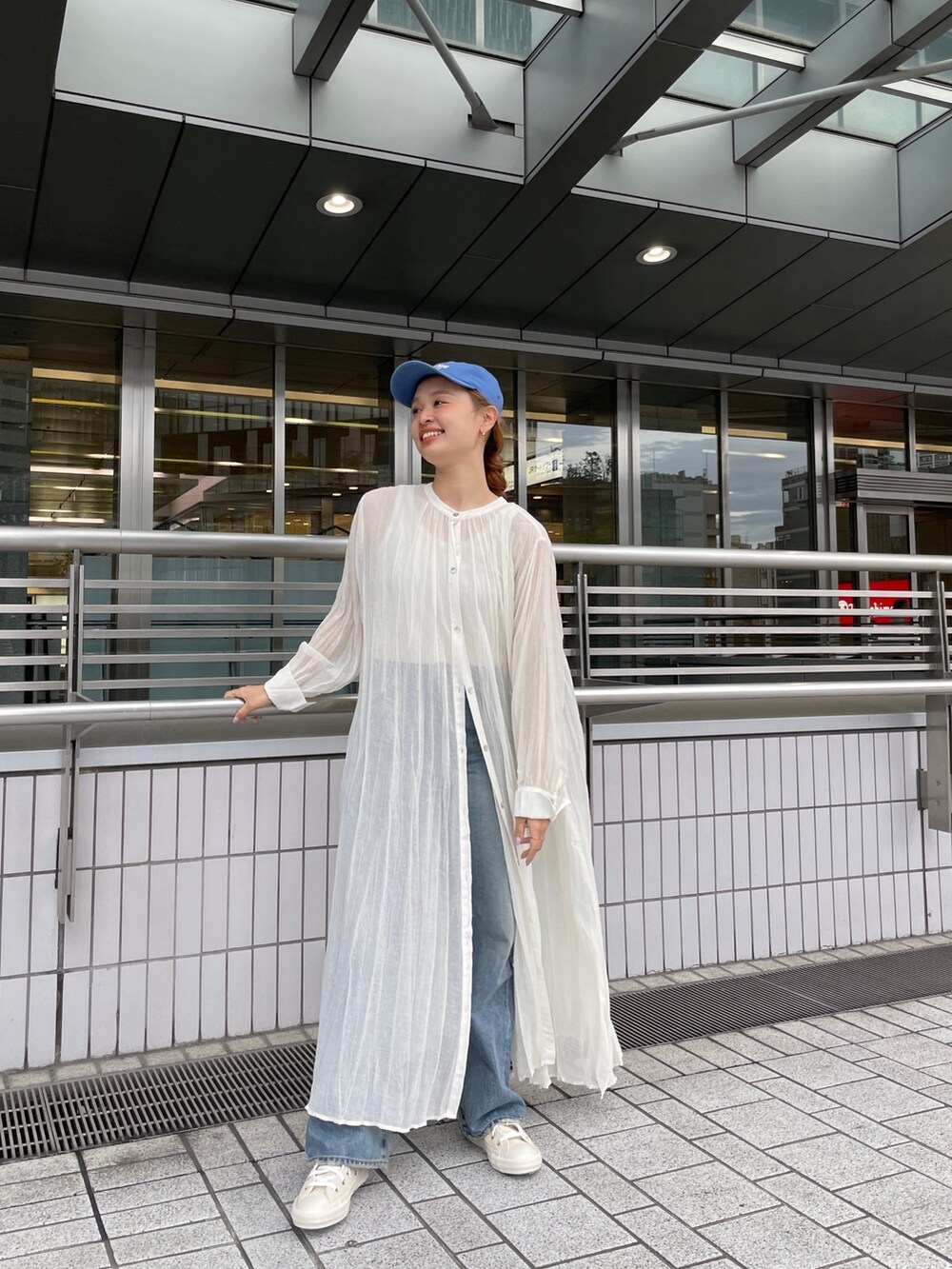 ブルー系のデニムパンツ、ホワイト系のスニーカー、ホワイト系のタンクトップを着用したレディースの春コーディネートの7枚目の写真