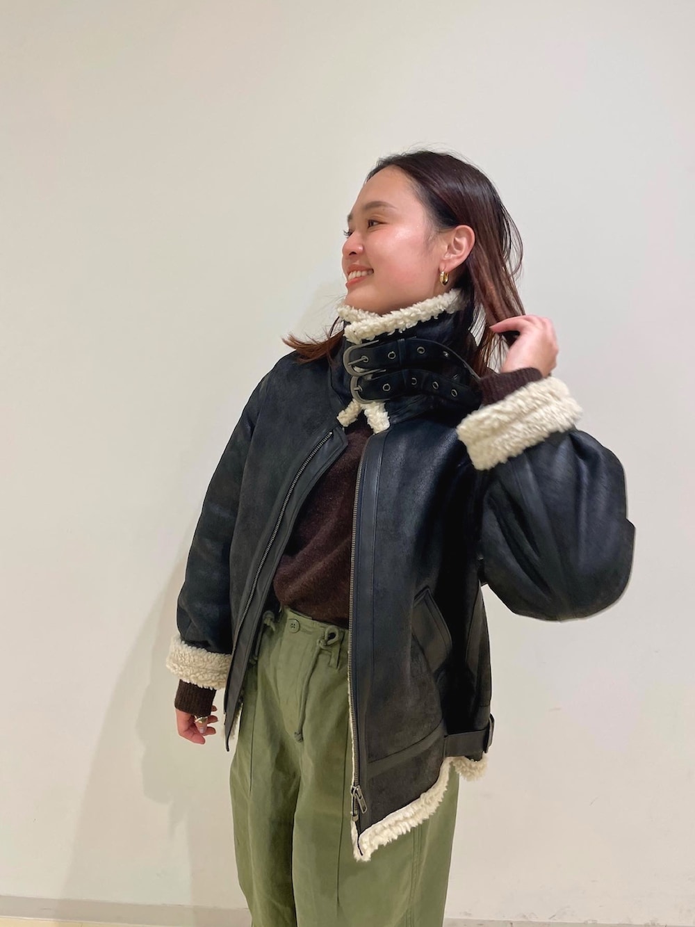 ブラウン系のムートンコート、パープル系のニット/セーター、ベージュ系のその他パンツを着用したレディースの冬コーディネートの3枚目の写真