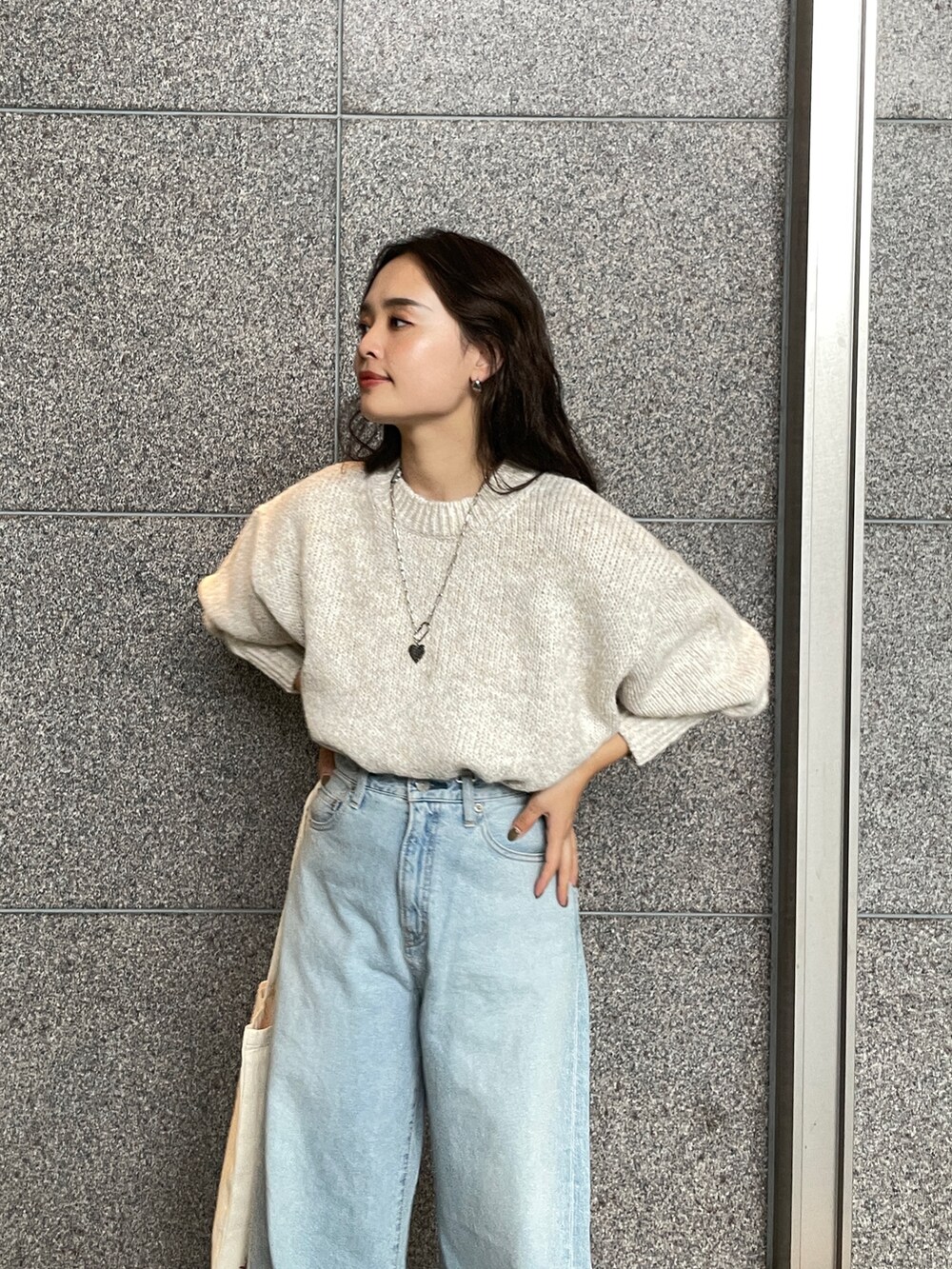ブルー系のデニムパンツ、ホワイト系のニット/セーター、レッド系のトートバッグを着用したレディースの秋コーディネートの8枚目の写真