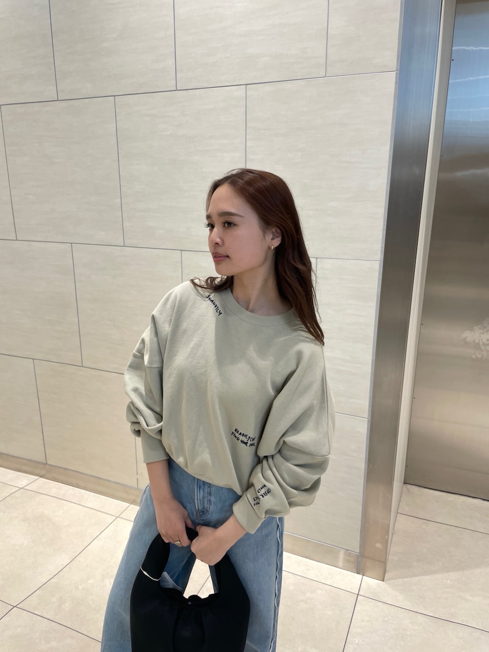 ベージュ系のスウェット、ブルー系のデニムパンツを着用したレディースの春コーディネートの3枚目の写真