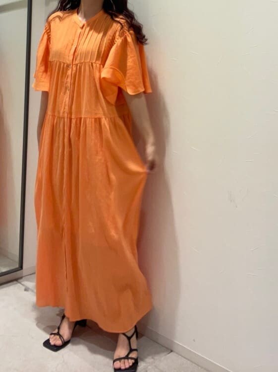 オレンジ系のワンピース、ベージュ系のハットを着用したレディースの春コーディネートの2枚目の写真