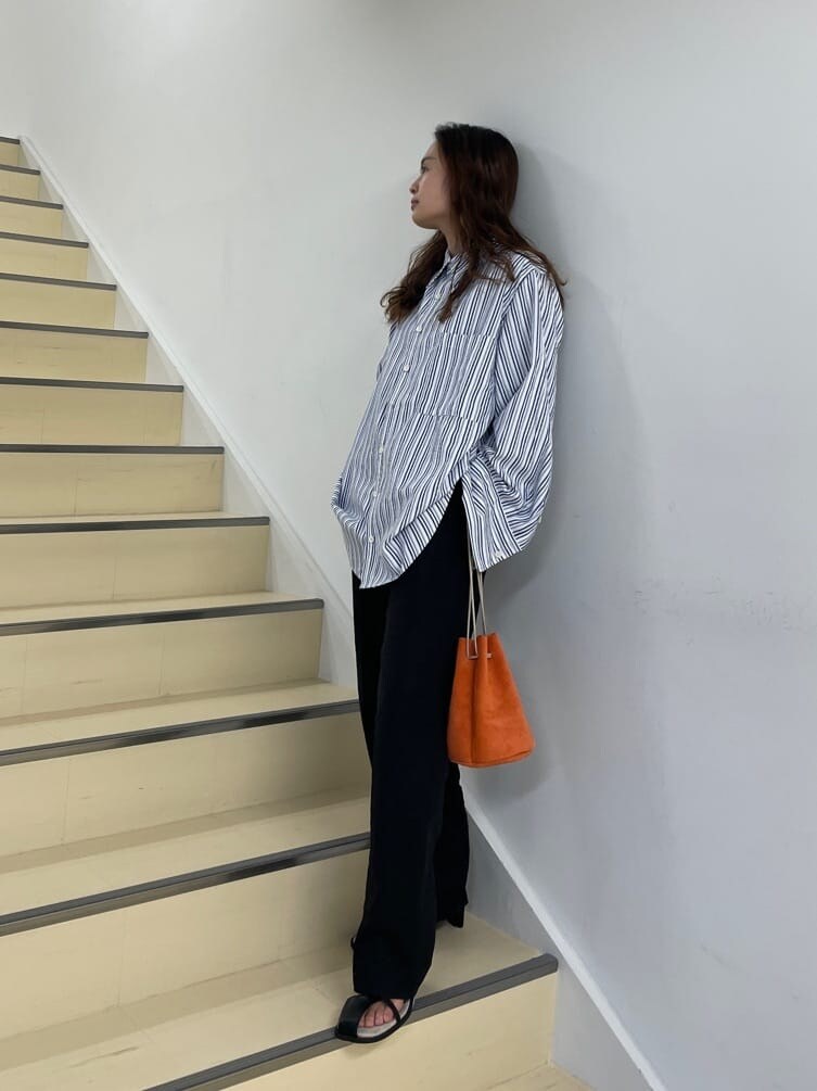 ブラック系のその他パンツ、ブルー系のシャツ/ブラウス、オレンジ系のハンドバッグを着用したレディースの春コーディネートの4枚目の写真