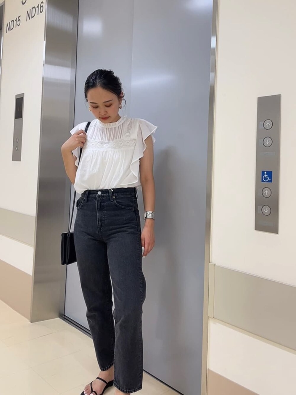 ブラック系のサンダル、ブラック系のショルダーバッグ、ブラック系のデニムパンツを着用したレディースの夏コーディネートの2枚目の写真