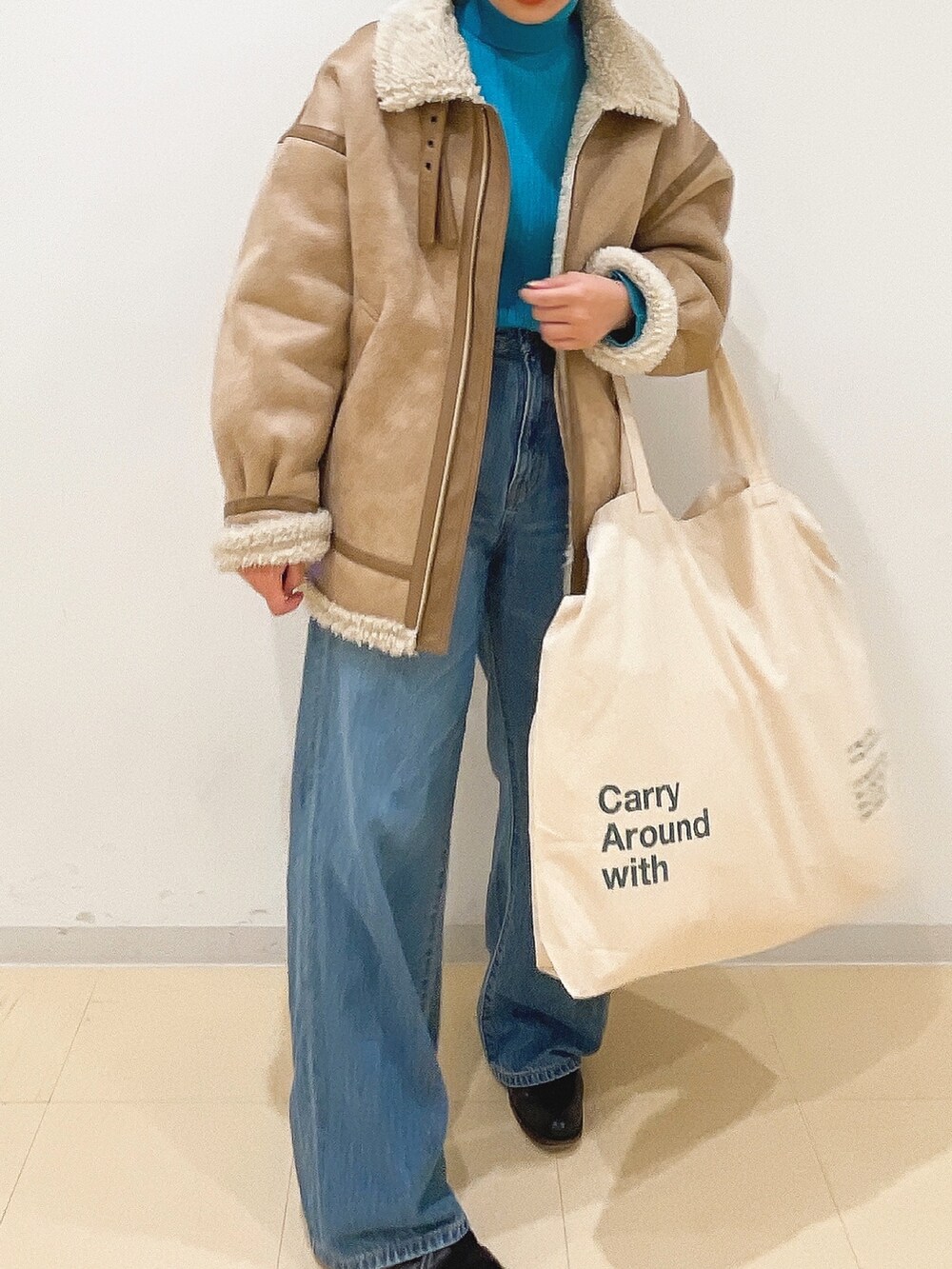 ベージュ系のムートンコート、ブルー系のニット/セーター、ホワイト系のハンドバッグを着用したレディースの冬コーディネートの6枚目の写真