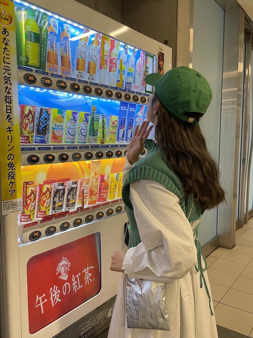 シルバー系のショルダーバッグ、グリーン系のワンピース、グリーン系のキャップを着用したレディースの冬コーディネートの6枚目の写真