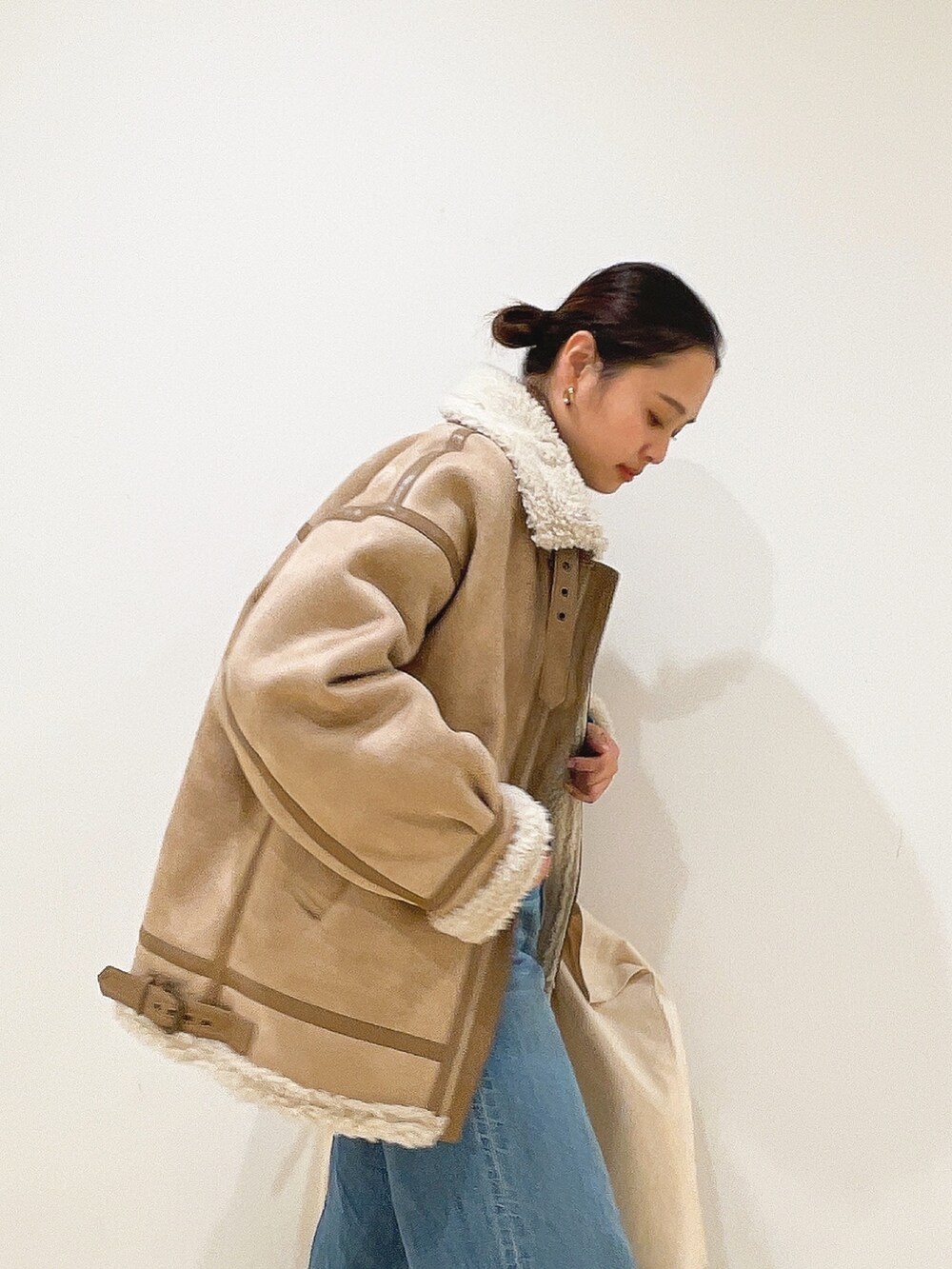 ベージュ系のムートンコート、ブルー系のニット/セーター、ホワイト系のハンドバッグを着用したレディースの冬コーディネートの7枚目の写真