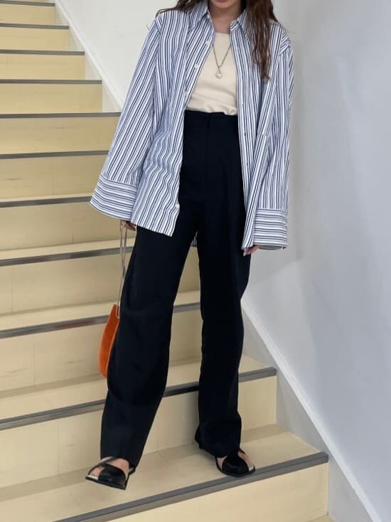 ブラック系のその他パンツ、ブルー系のシャツ/ブラウス、オレンジ系のハンドバッグを着用したレディースの春コーディネートの3枚目の写真