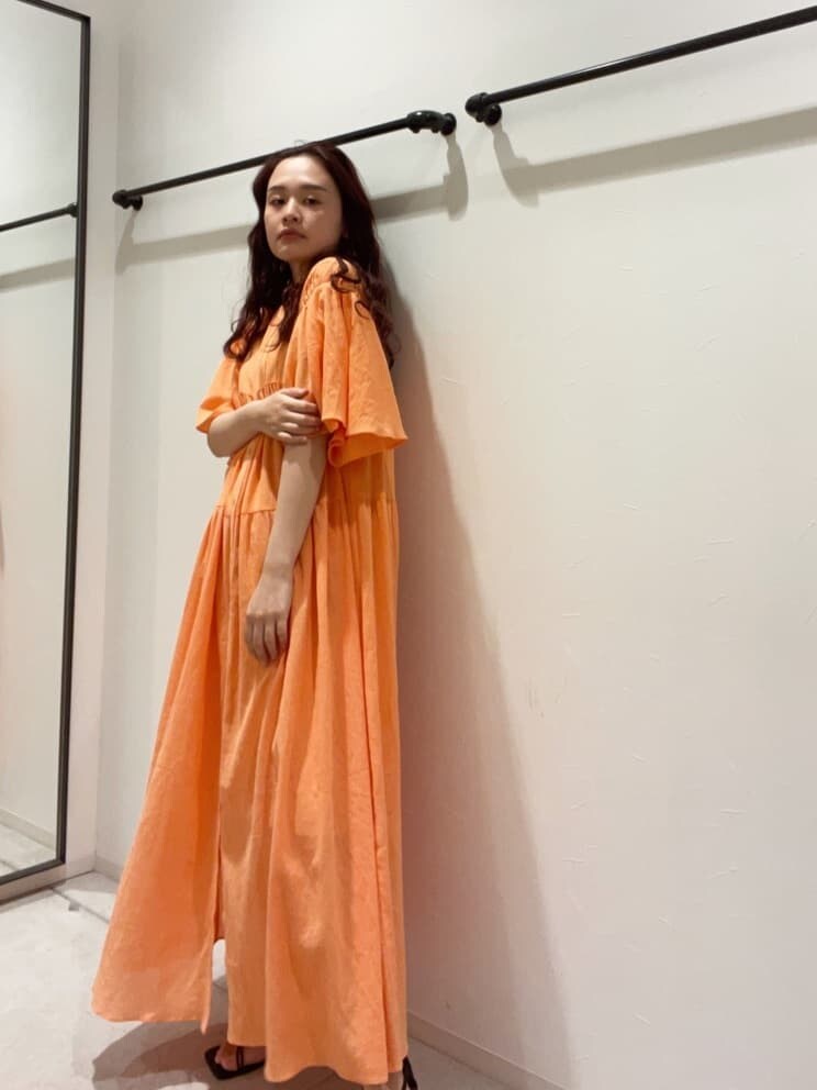 オレンジ系のワンピース、ベージュ系のハットを着用したレディースの春コーディネートの5枚目の写真