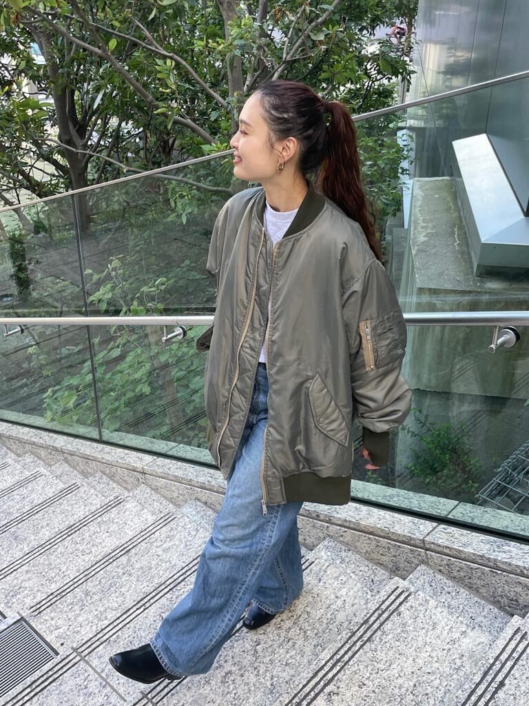 ブルー系のデニムパンツ、ブラック系のブーツ、グリーン系のMA-1を着用したレディースの秋コーディネートの4枚目の写真