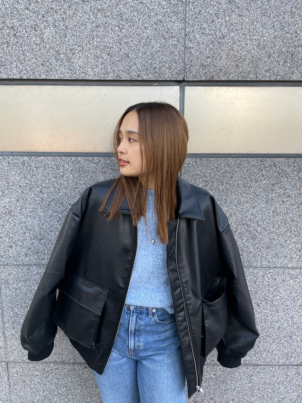 ブラック系のブルゾン、ブルー系のニット/セーター、ブルー系のデニムパンツを着用したレディースの秋コーディネートの5枚目の写真