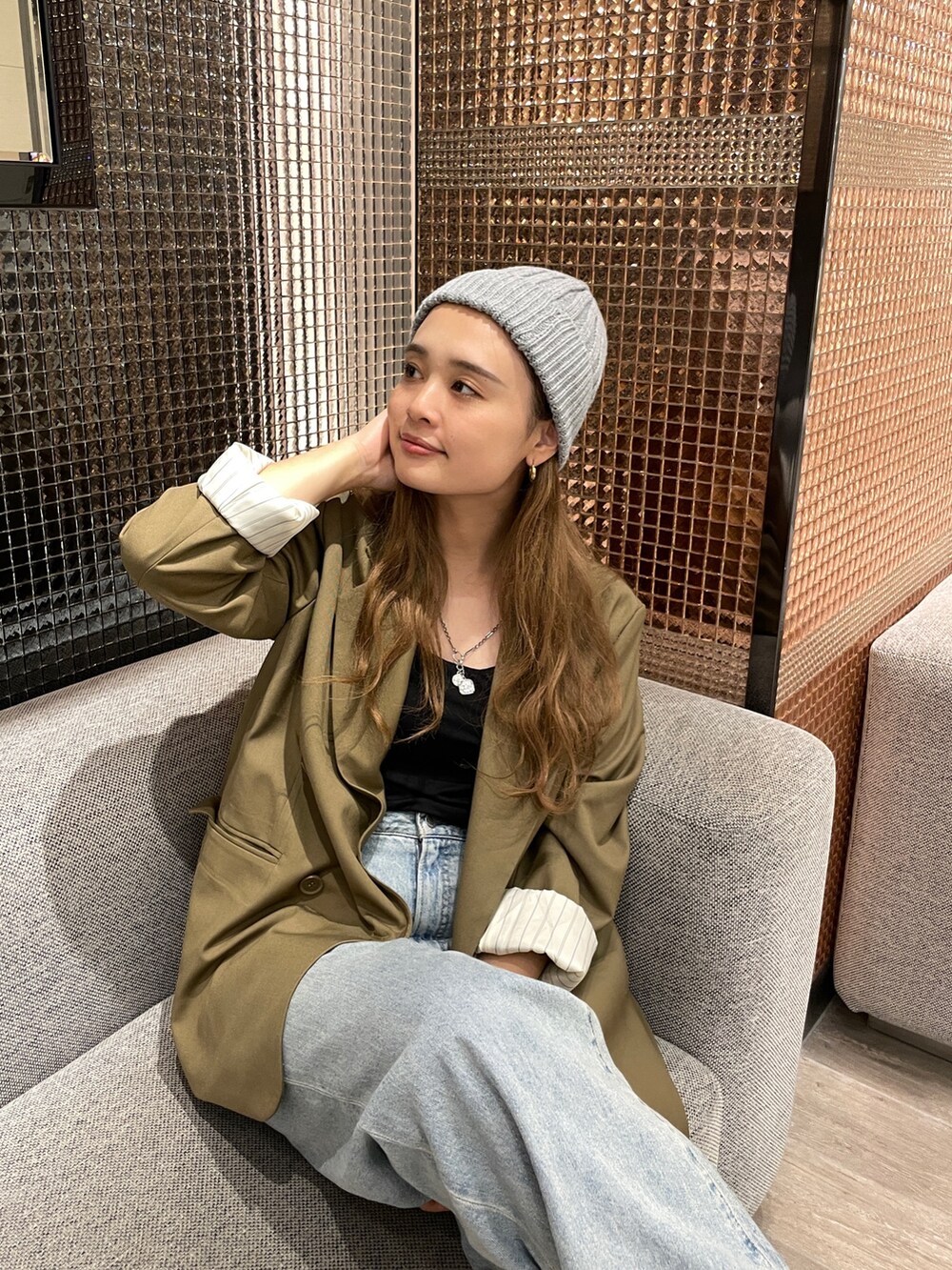 グリーン系のテーラードジャケット、ブルー系のデニムパンツ、グレー系のニットキャップ/ビーニーを着用したレディースの秋コーディネートの2枚目の写真