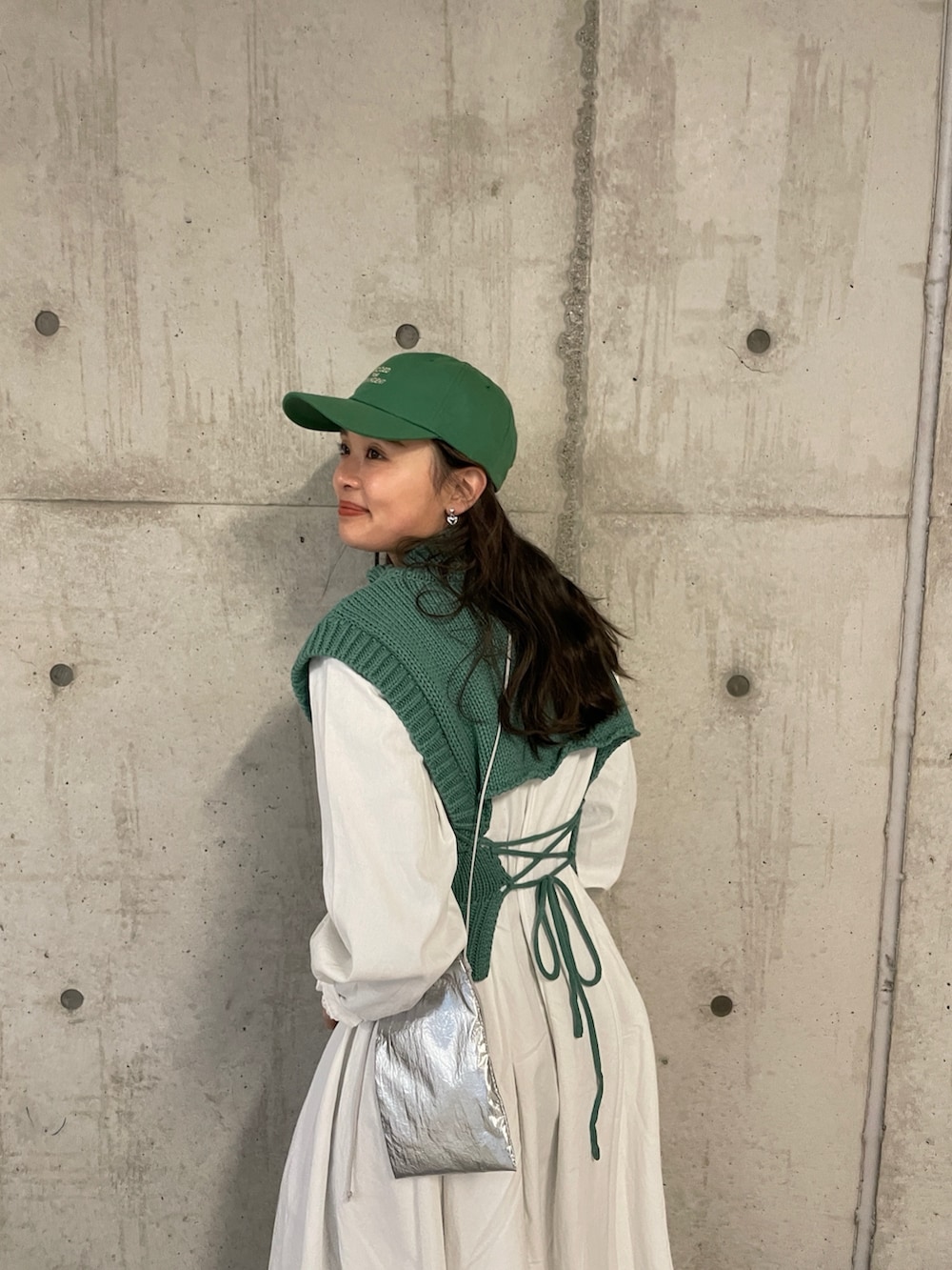 シルバー系のショルダーバッグ、グリーン系のワンピース、グリーン系のキャップを着用したレディースの冬コーディネートの4枚目の写真