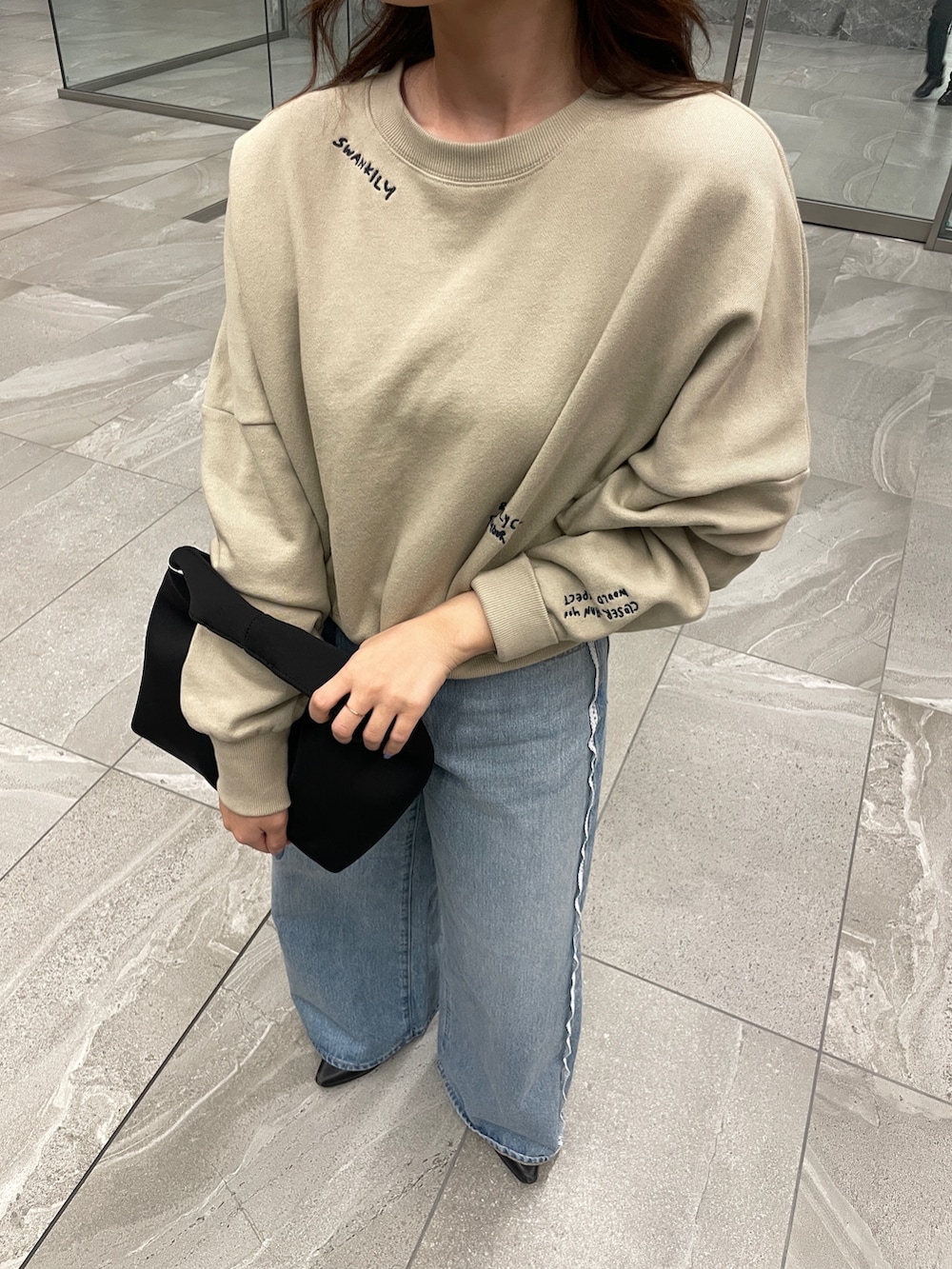 ベージュ系のスウェット、ブルー系のデニムパンツを着用したレディースの春コーディネートの5枚目の写真