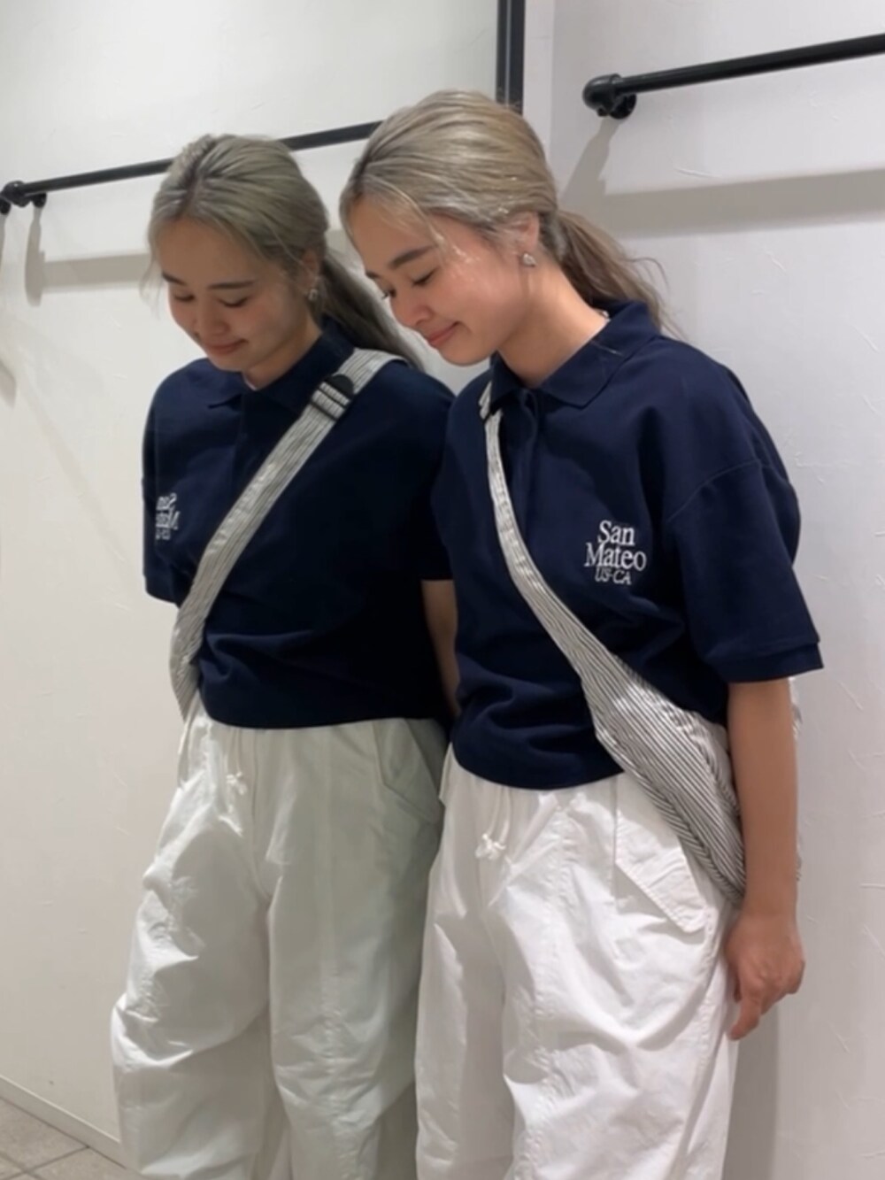 ブルー系のポロシャツ、ホワイト系のその他パンツ、その他のショルダーバッグを着用したレディースの夏コーディネートの2枚目の写真