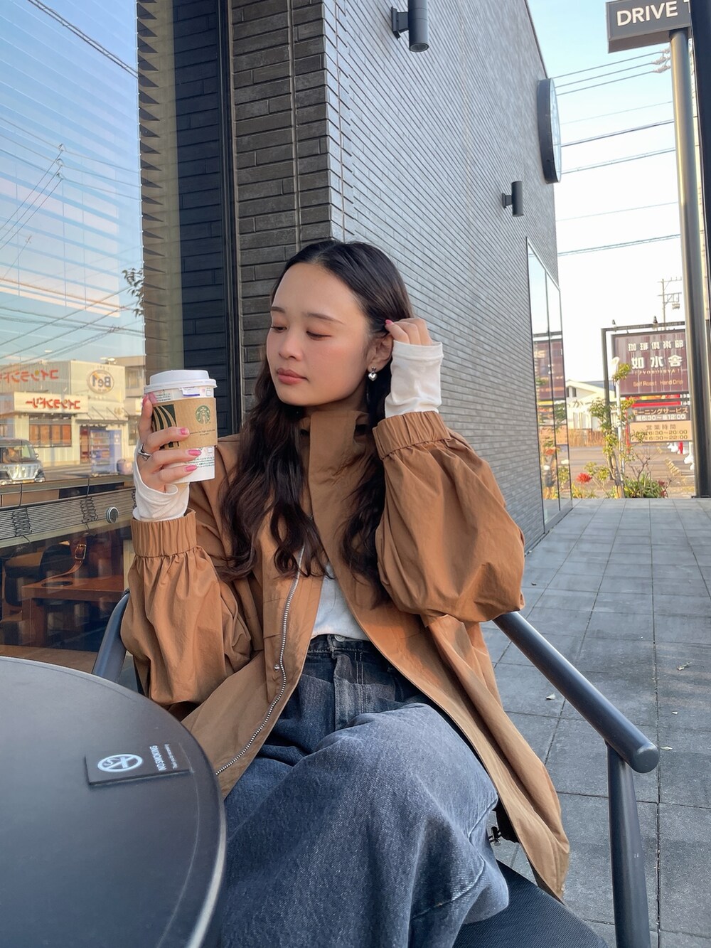 ブラック系のデニムパンツ、ベージュ系のブルゾン、ホワイト系のTシャツ/カットソーを着用したレディースの冬コーディネートの2枚目の写真