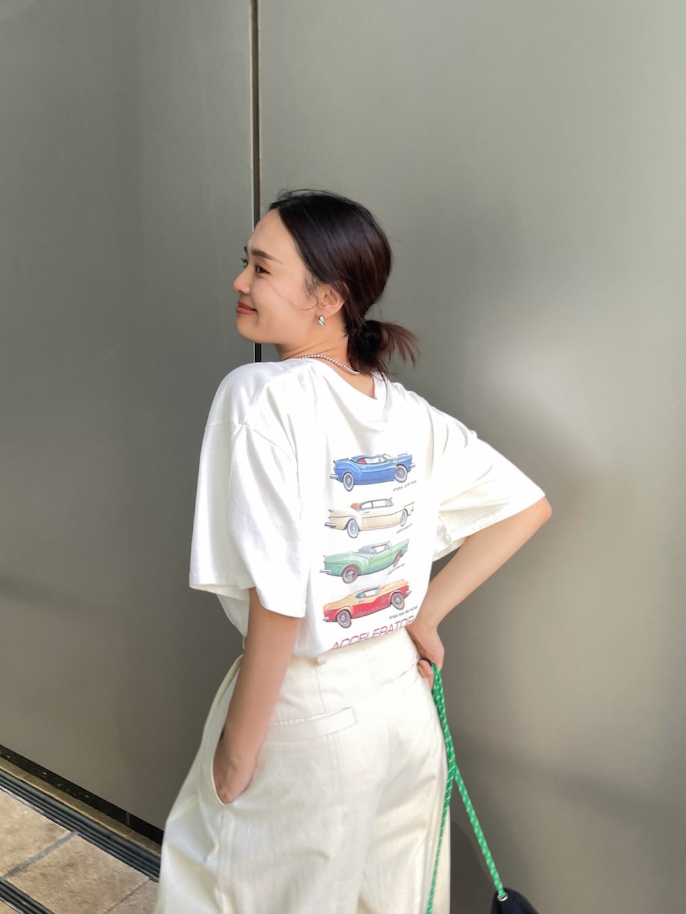 ホワイト系のTシャツ/カットソー、ホワイト系のチノパンツ、ブラック系のバックパック/リュックを着用したレディースの夏コーディネートの2枚目の写真