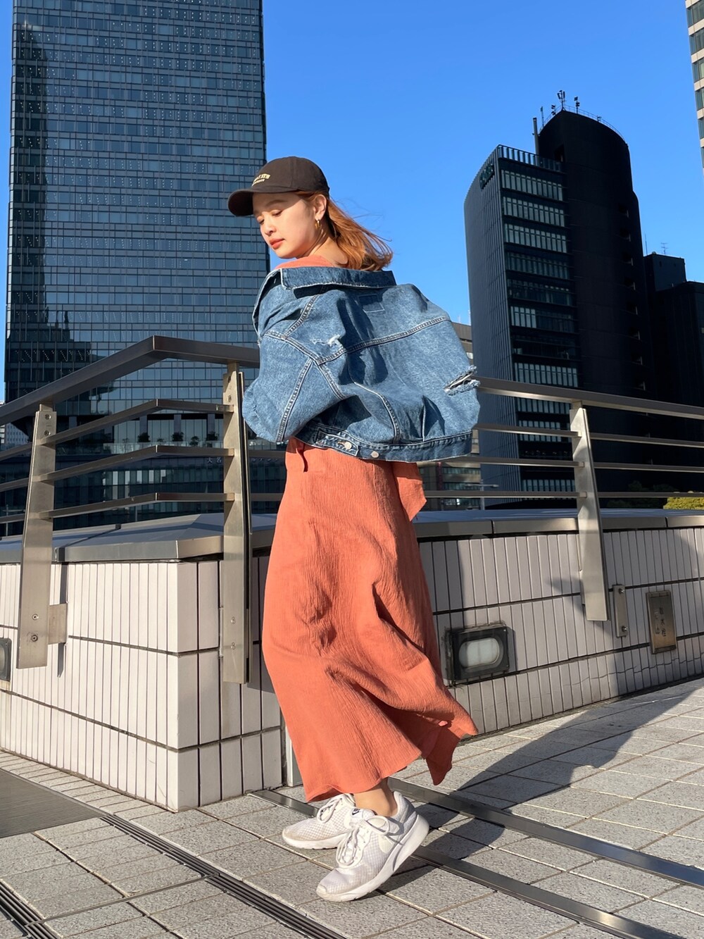 オレンジ系のワンピース、ブルー系のデニムジャケットを着用したレディースの春コーディネートの9枚目の写真