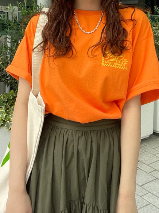 ベージュ系のスカート、オレンジ系のTシャツ/カットソー、グリーン系のハンドバッグを着用したレディースの春コーディネートの5枚目の写真