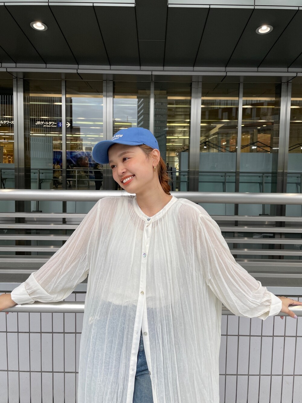ブルー系のデニムパンツ、ホワイト系のスニーカー、ホワイト系のタンクトップを着用したレディースの春コーディネートの2枚目の写真