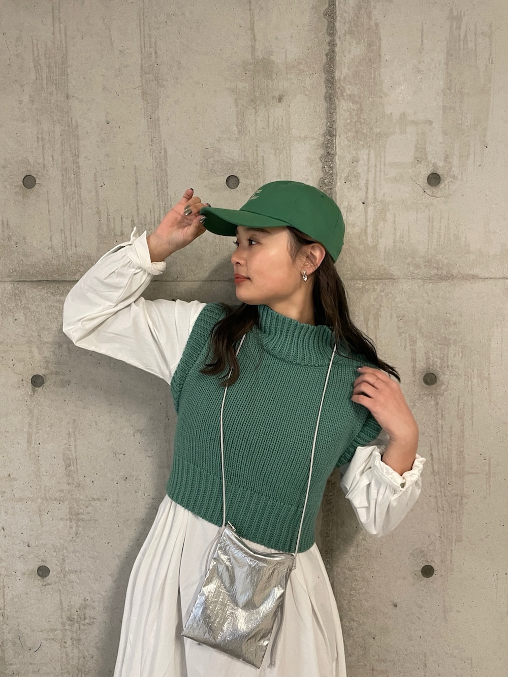 シルバー系のショルダーバッグ、グリーン系のワンピース、グリーン系のキャップを着用したレディースの冬コーディネートの3枚目の写真
