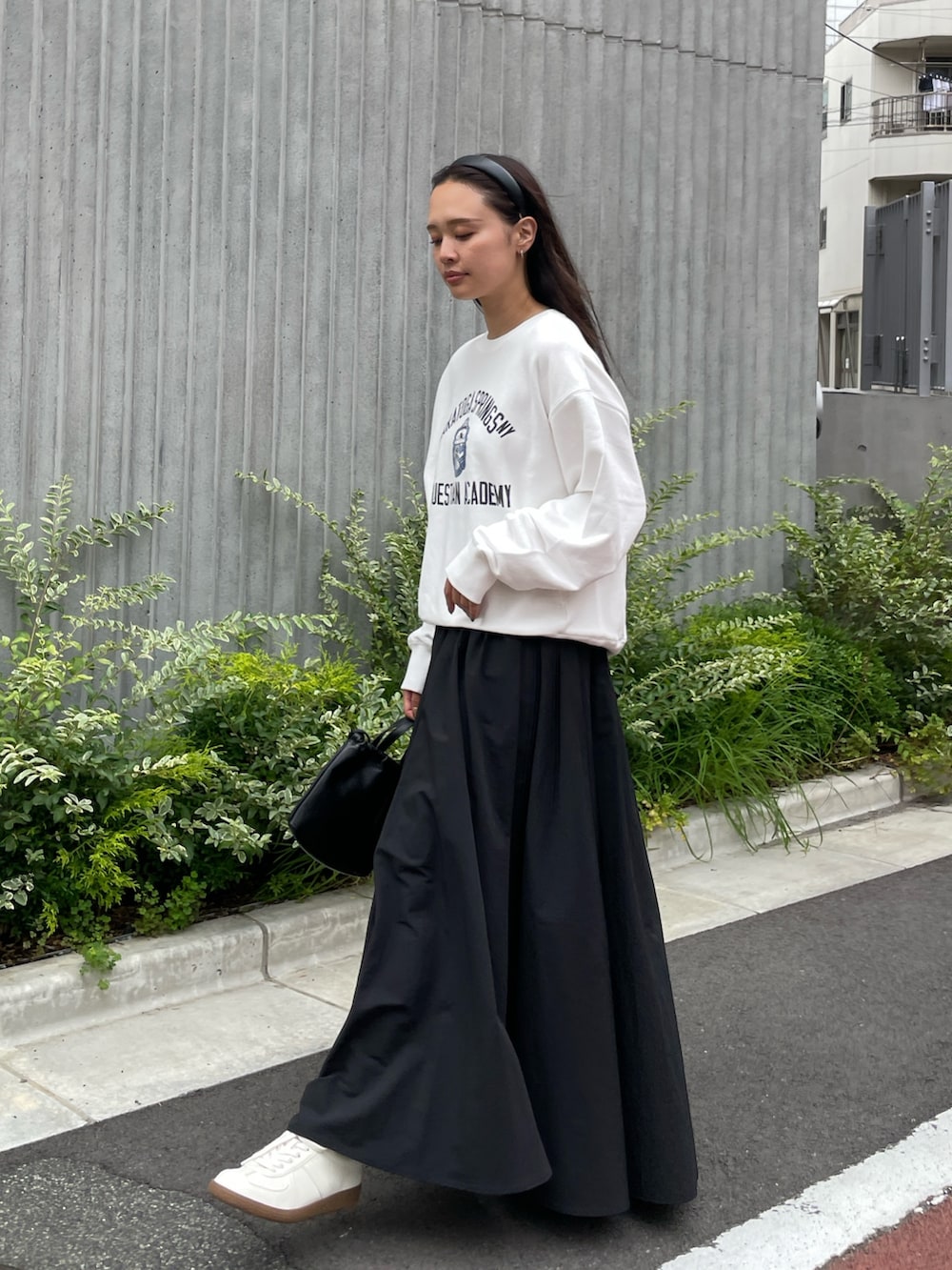 ホワイト系のスウェット、ブラック系のスカート、ブラック系のショルダーバッグを着用したレディースの夏コーディネートの6枚目の写真