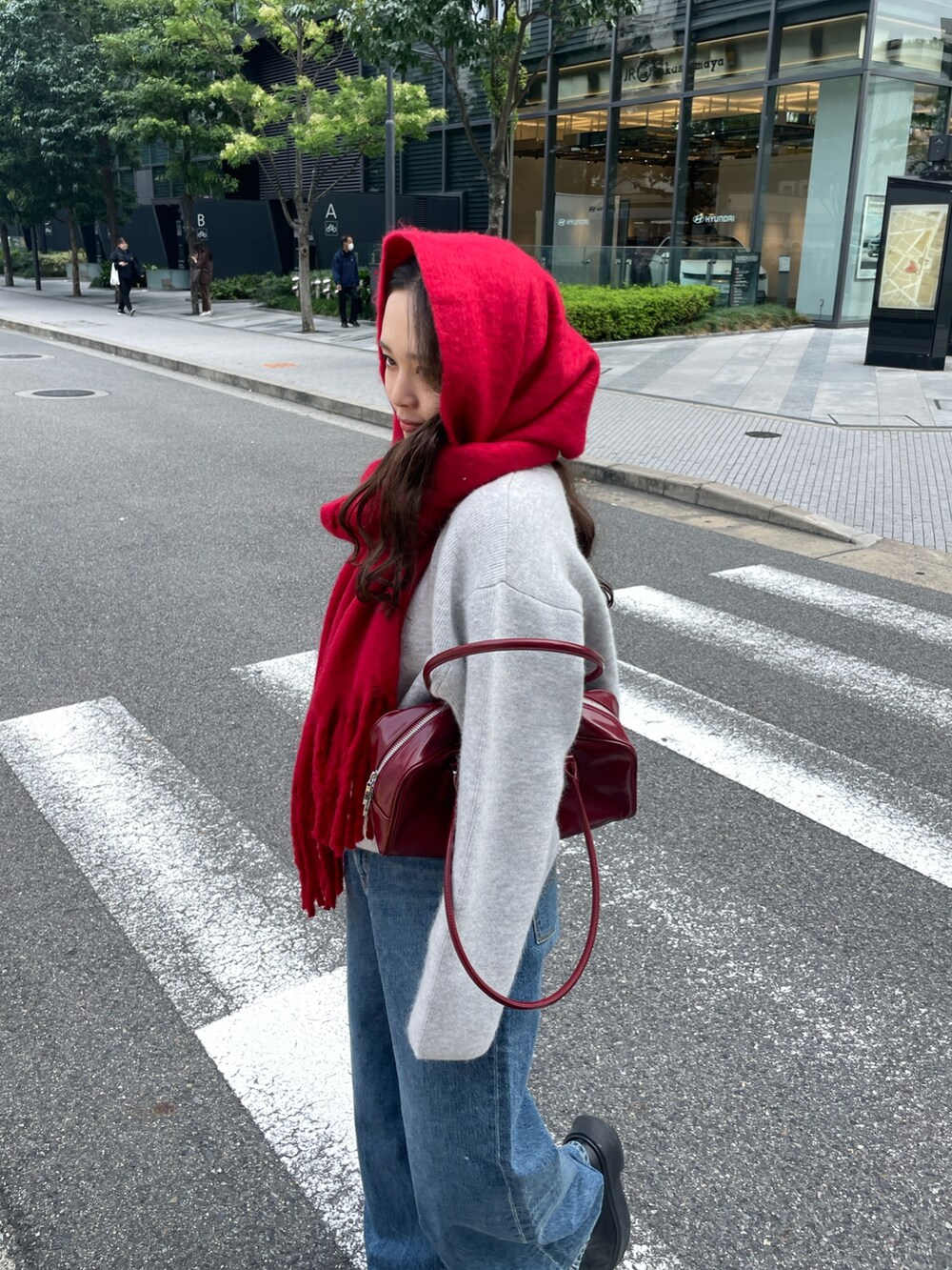 ブルー系のデニムパンツ、レッド系のハンドバッグ、グレー系のカーディガン/ボレロを着用したレディースの秋コーディネートの3枚目の写真