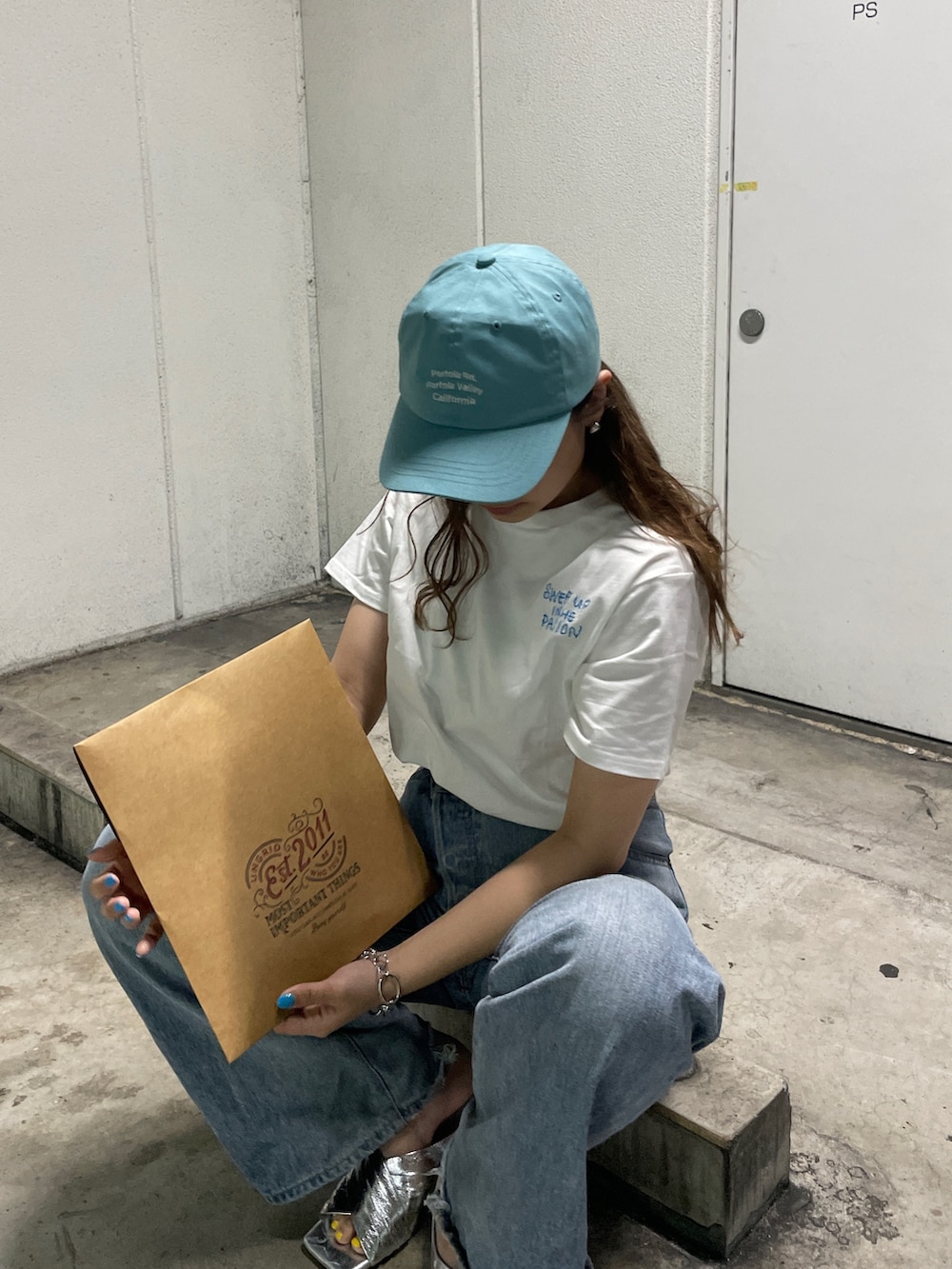 ブルー系のデニムパンツ、シルバー系のサンダル、ブルー系のキャップを着用したレディースの春コーディネートの2枚目の写真