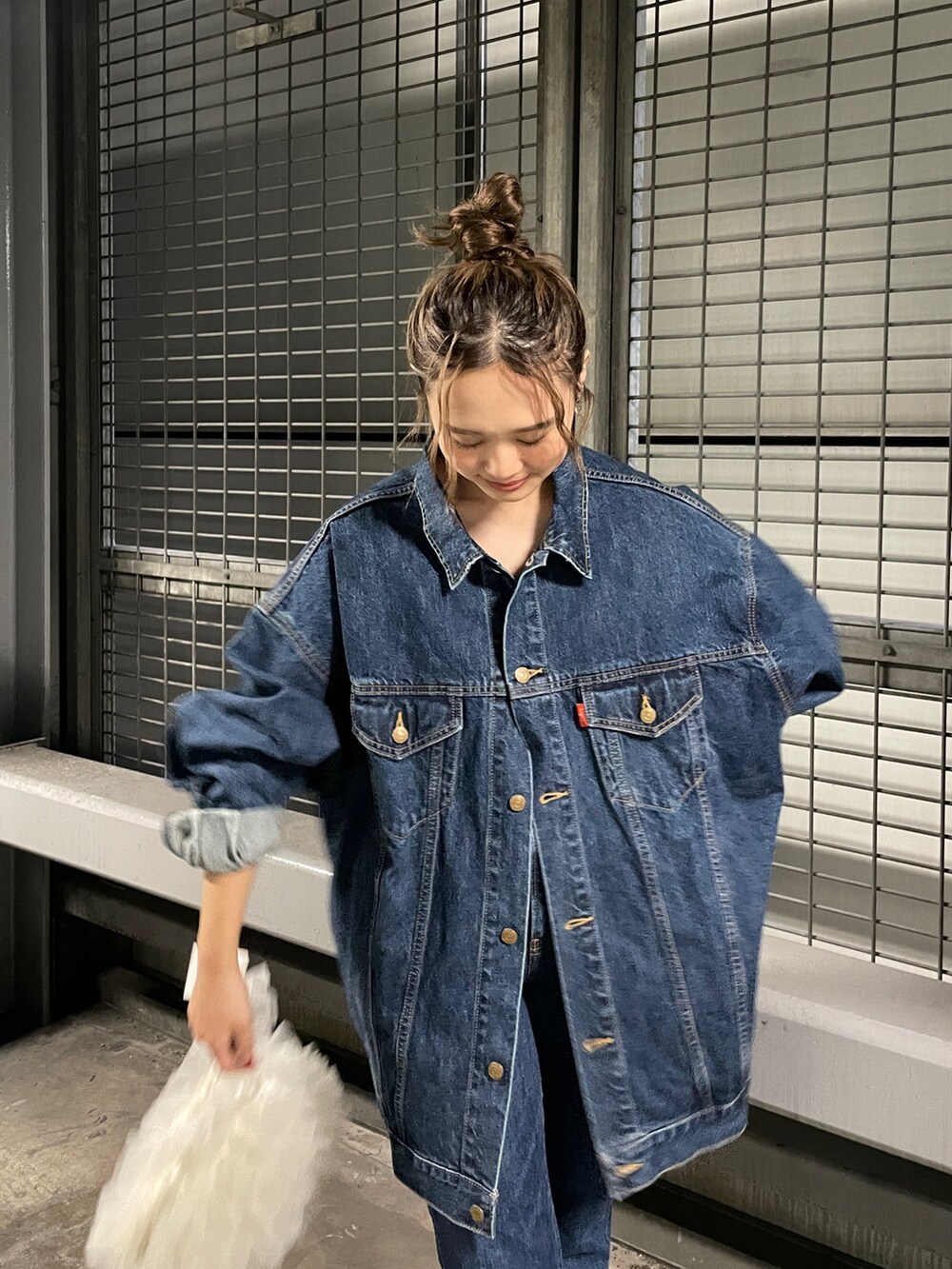 ホワイト系のショルダーバッグ、ブルー系のデニムジャケット、ブルー系のデニムパンツを着用したレディースの夏コーディネートの3枚目の写真