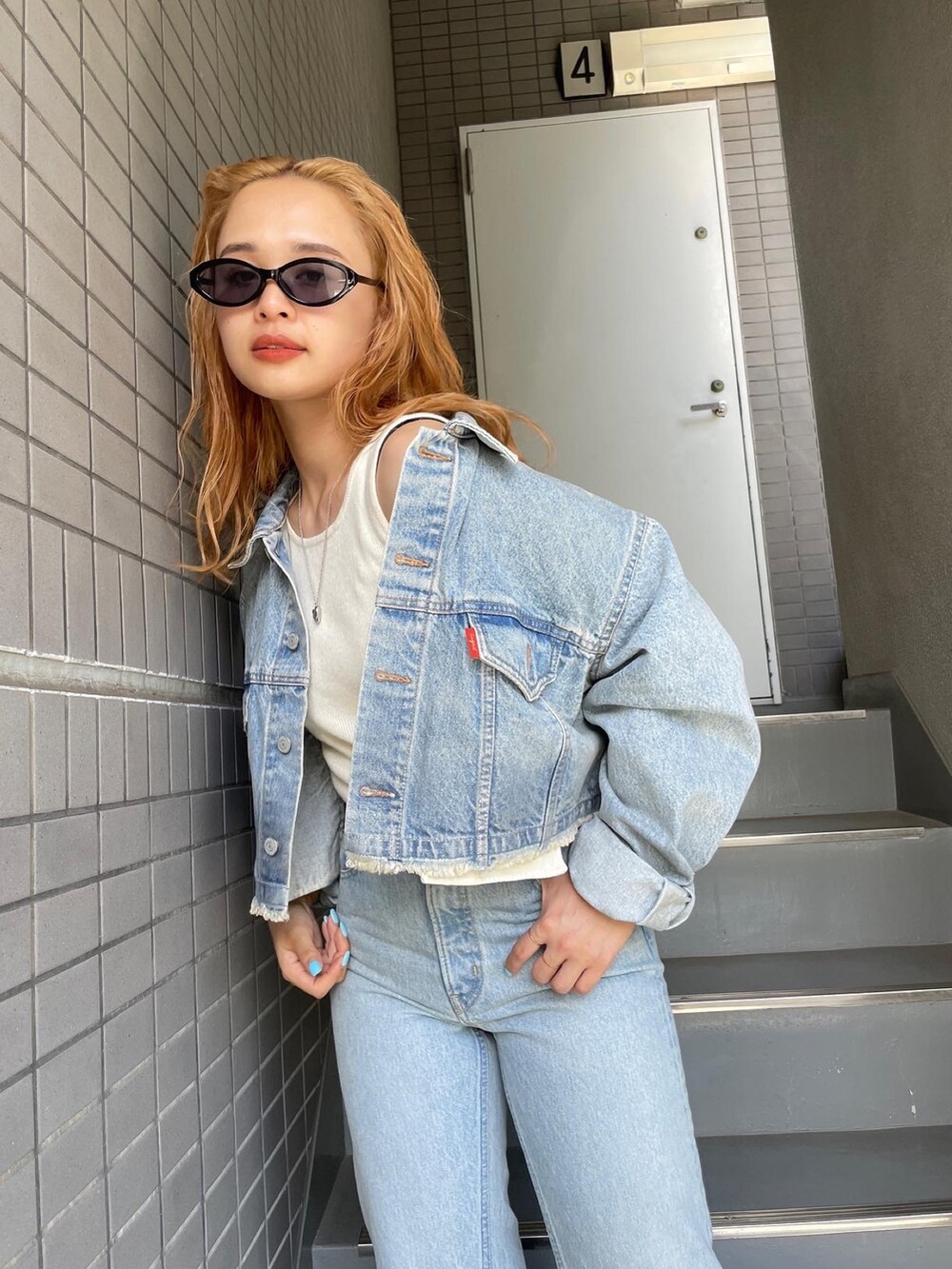 ブルー系のデニムパンツ、ブルー系のデニムジャケット、ブラック系のサングラスを着用したレディースの夏コーディネートの3枚目の写真