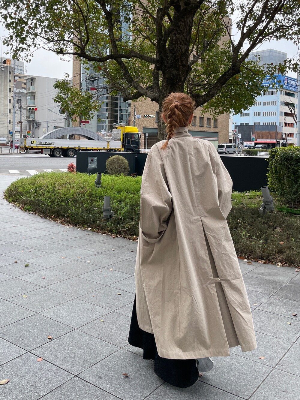 グリーン系のワンピース、ブルー系のトートバッグ、ベージュ系のステンカラーコートを着用したレディースの春コーディネートの4枚目の写真