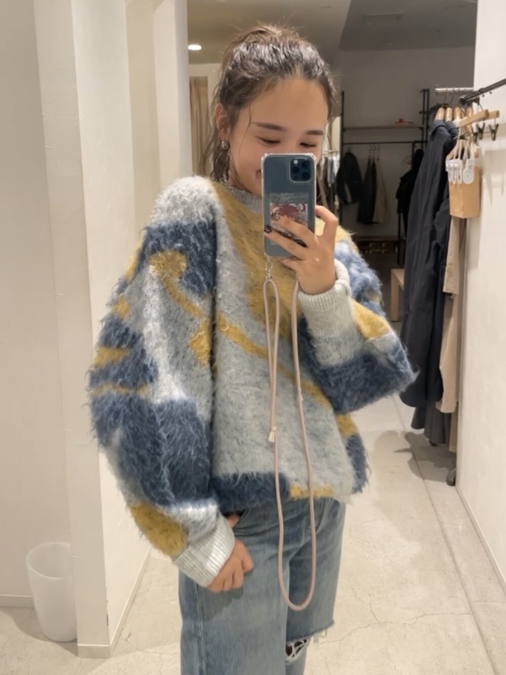 ブルー系のニット/セーター、ブルー系のデニムパンツ、ブラック系のブーツを着用したレディースの秋コーディネートの3枚目の写真