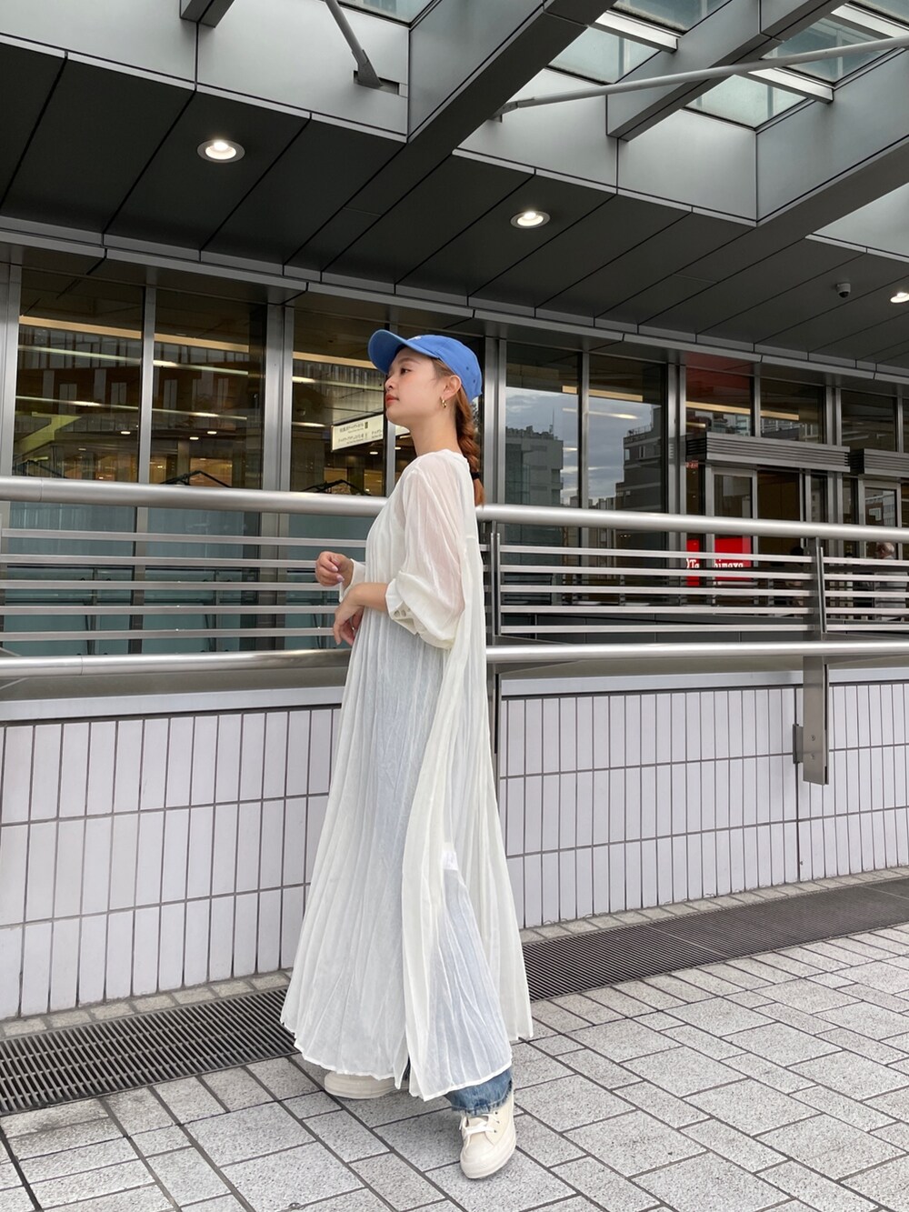 ブルー系のデニムパンツ、ホワイト系のスニーカー、ホワイト系のタンクトップを着用したレディースの春コーディネートの6枚目の写真