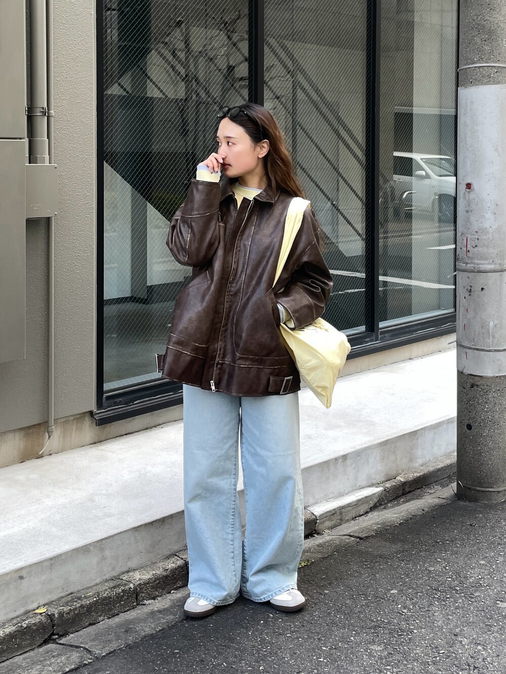 ブラウン系のブルゾン、ブルー系のデニムパンツ、イエロー系のエコバッグ/サブバッグを着用したレディースの冬コーディネートの2枚目の写真