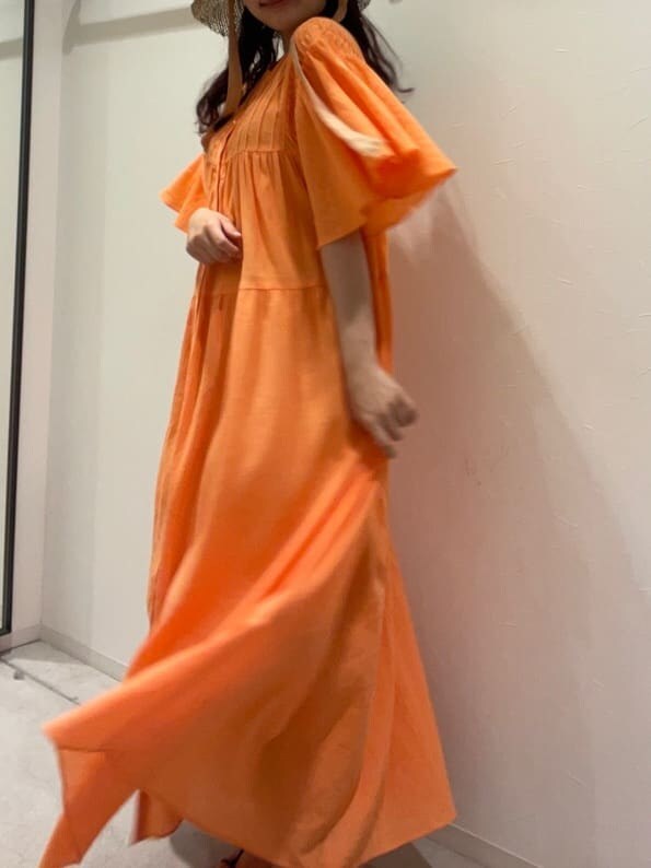 オレンジ系のワンピース、ベージュ系のハットを着用したレディースの春コーディネートの6枚目の写真